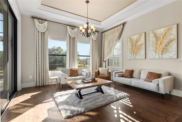 living area featuring dark hardwood / wood-style flooring, crown molding, a raised ceiling, and a notable chandelier