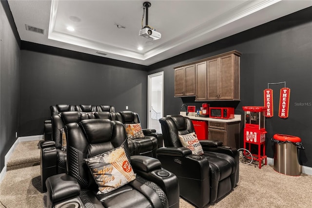 home theater featuring crown molding, a tray ceiling, light carpet, and built in desk