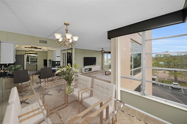 dining space featuring ceiling fan with notable chandelier and a textured ceiling