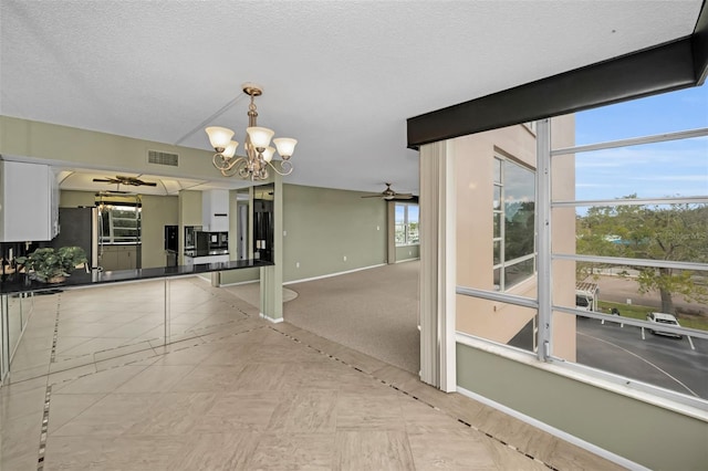 kitchen featuring hanging light fixtures, white cabinets, stainless steel fridge, and ceiling fan with notable chandelier