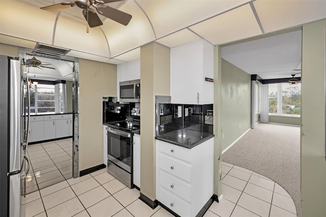 kitchen with light carpet, white cabinetry, ceiling fan, appliances with stainless steel finishes, and dark stone countertops