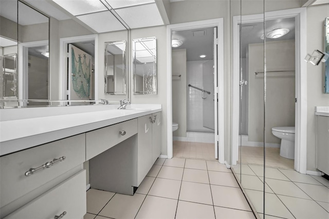 bathroom with toilet, vanity, tile patterned floors, and a shower with door