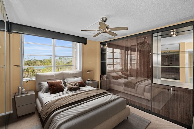 carpeted bedroom with ceiling fan and a textured ceiling