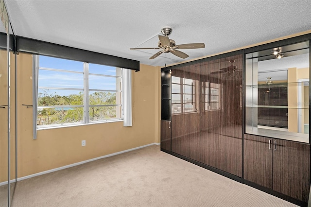 spare room with a textured ceiling, ceiling fan, and light colored carpet