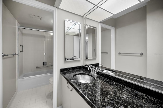 full bathroom featuring tile patterned floors, bath / shower combo with glass door, toilet, and vanity