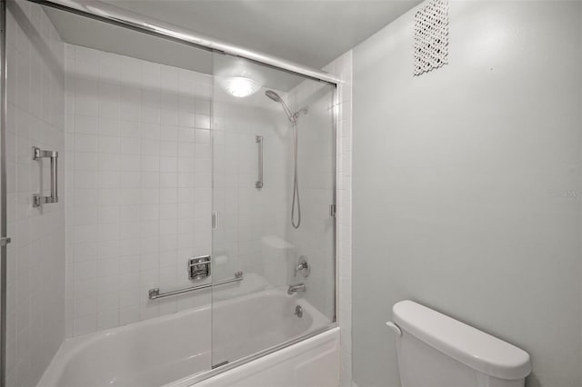 bathroom featuring toilet and shower / bath combination with glass door