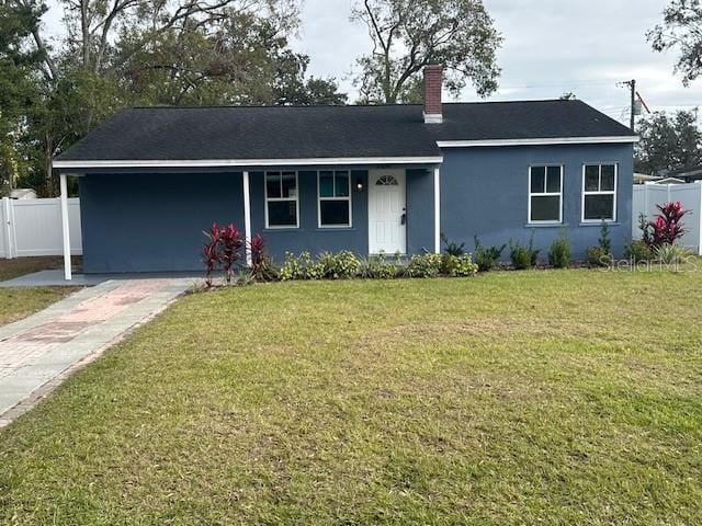 ranch-style house featuring a front lawn and a carport