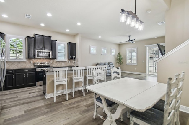 dining space featuring light wood-type flooring, ceiling fan, and sink