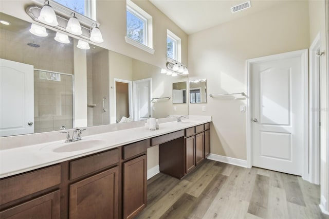 bathroom with hardwood / wood-style floors, a shower with shower door, and vanity