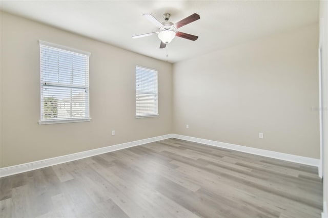 spare room featuring ceiling fan, light wood-type flooring, and a wealth of natural light