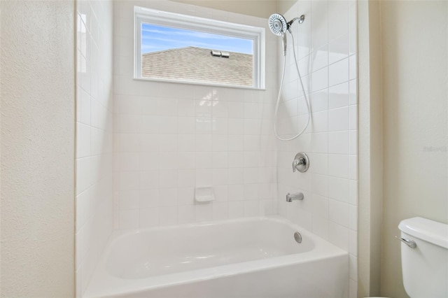 bathroom featuring tiled shower / bath combo and toilet