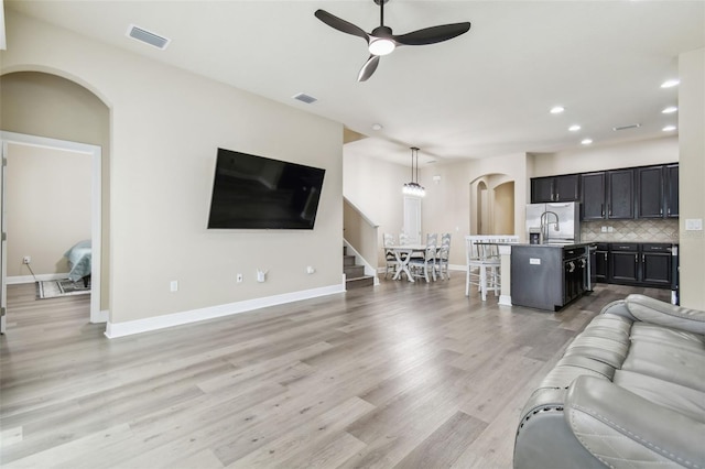 living room with sink, ceiling fan, and light wood-type flooring