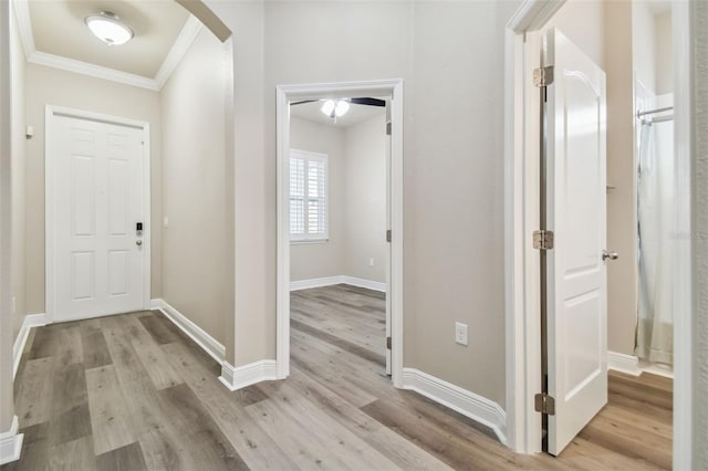 entryway with crown molding, wood finished floors, arched walkways, and baseboards