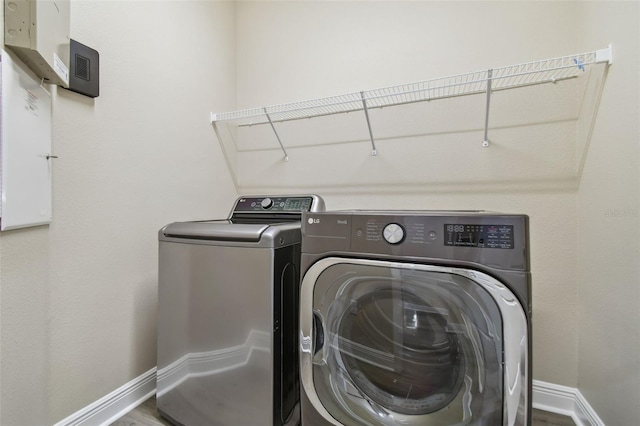 laundry area featuring laundry area, wood finished floors, baseboards, and washer and clothes dryer