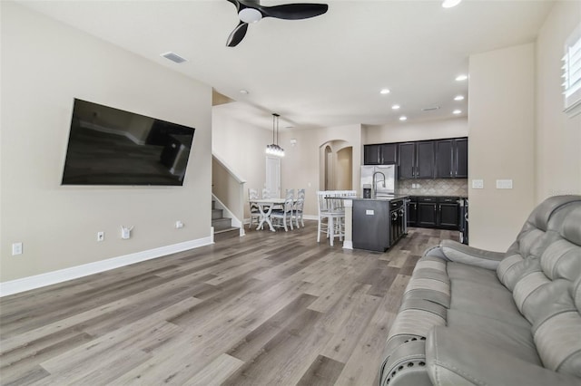 living room with visible vents, ceiling fan, baseboards, recessed lighting, and light wood-style floors