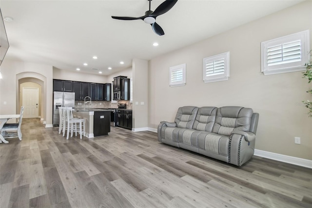 living area with recessed lighting, light wood-style floors, baseboards, and ceiling fan