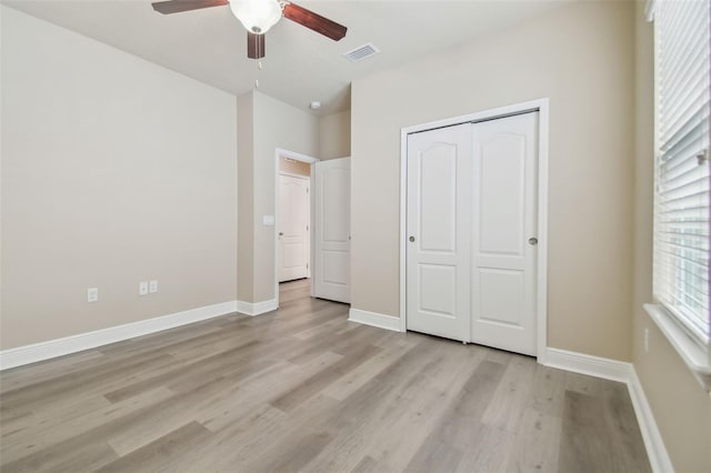 unfurnished bedroom featuring light wood-style floors, visible vents, a closet, and baseboards