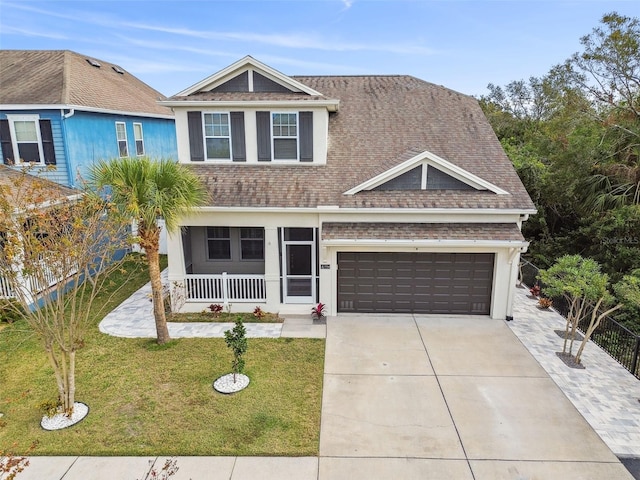 view of front facade featuring covered porch, roof with shingles, an attached garage, concrete driveway, and a front yard