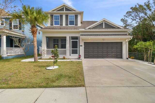 craftsman-style home featuring a garage, a porch, concrete driveway, and a front yard