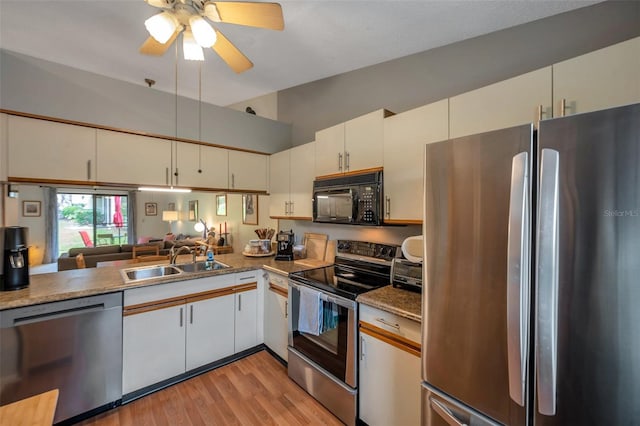 kitchen with appliances with stainless steel finishes, light wood-type flooring, ceiling fan, white cabinets, and sink