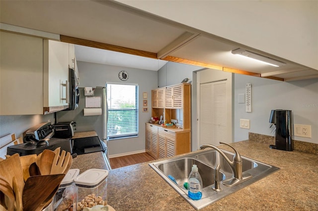 kitchen with range, wood-type flooring, beamed ceiling, sink, and white cabinetry