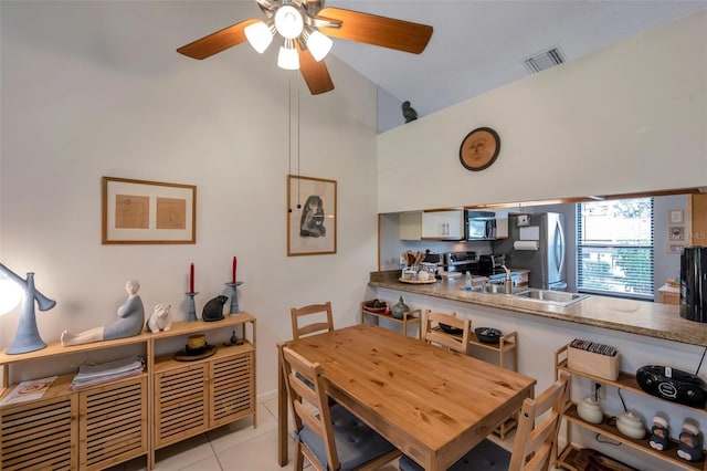 tiled dining room with ceiling fan and sink