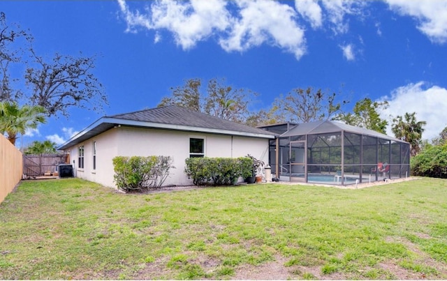 rear view of property featuring a fenced in pool, a fenced backyard, stucco siding, a lanai, and a lawn