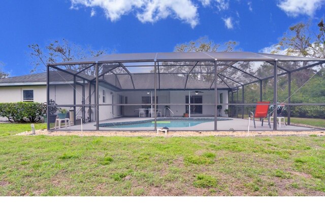 rear view of house with glass enclosure, a patio, a lawn, and an outdoor pool