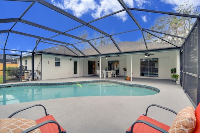 outdoor pool with a patio area, glass enclosure, and ceiling fan