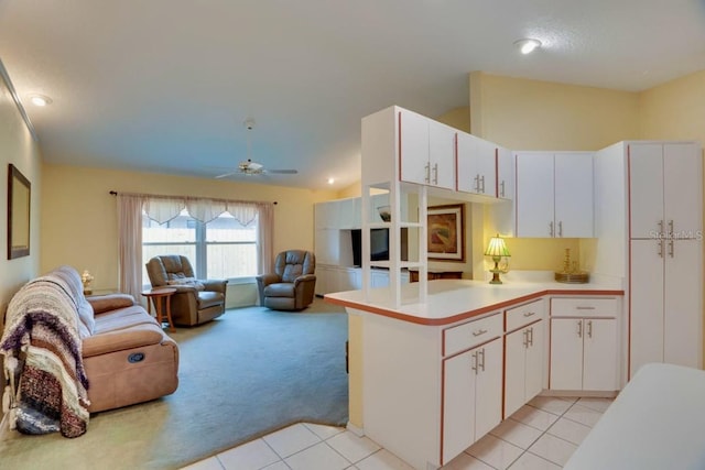 kitchen with open floor plan, light countertops, light carpet, light tile patterned floors, and a peninsula