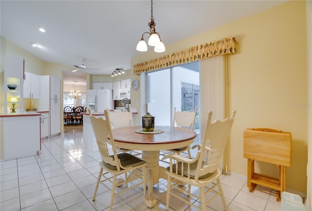 dining area with light tile patterned floors, baseboards, a healthy amount of sunlight, and ceiling fan with notable chandelier