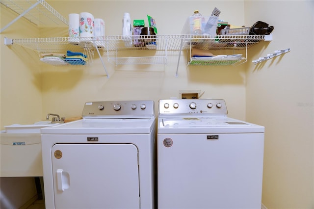 clothes washing area featuring laundry area, washing machine and dryer, and a sink