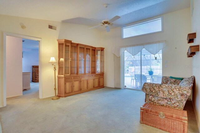 sitting room featuring a towering ceiling, visible vents, carpet floors, and ceiling fan