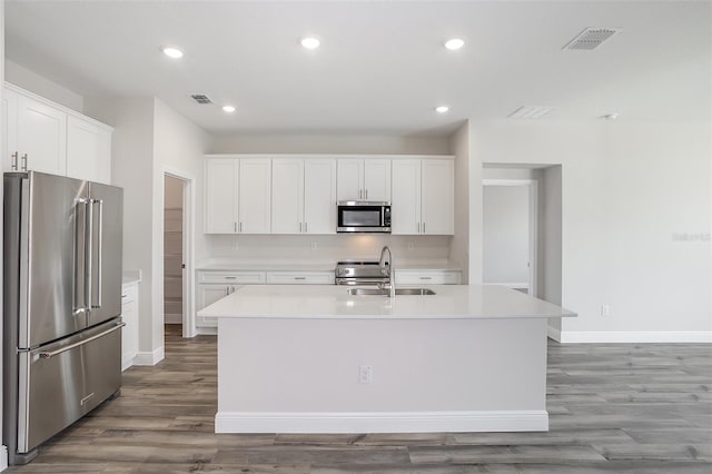 kitchen featuring stainless steel appliances, wood finished floors, a sink, visible vents, and light countertops