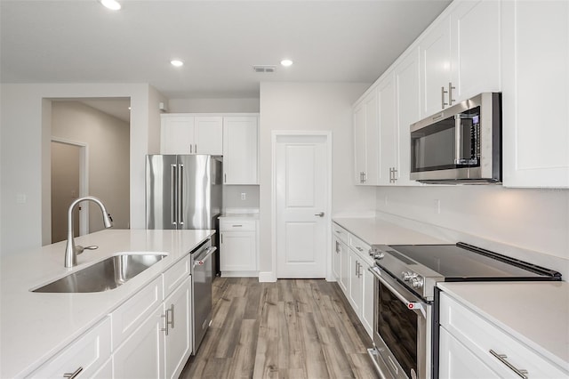 kitchen with visible vents, light wood-style flooring, high quality appliances, light countertops, and a sink