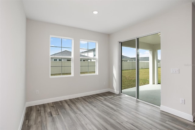 spare room with recessed lighting, baseboards, and wood finished floors