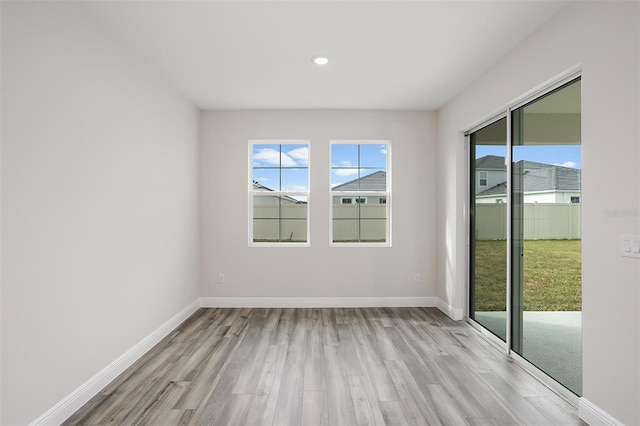 spare room with baseboards, light wood-style floors, and a healthy amount of sunlight