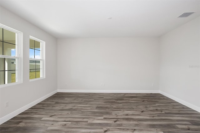 spare room featuring baseboards, visible vents, and wood finished floors