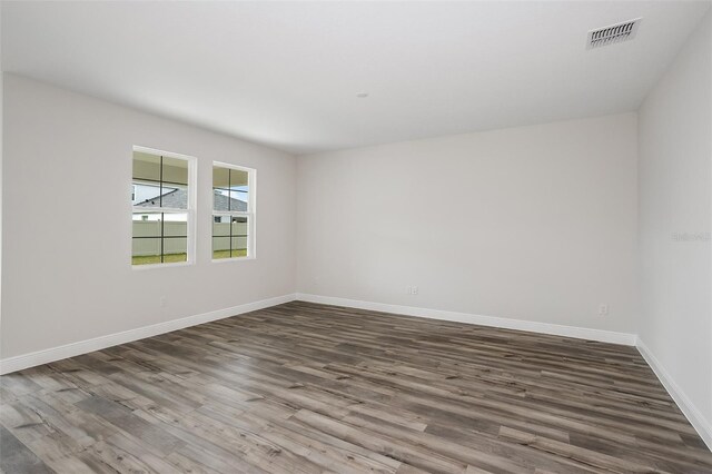 unfurnished room featuring baseboards, visible vents, and dark wood-type flooring