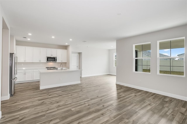 kitchen with stainless steel appliances, a sink, baseboards, open floor plan, and light wood-type flooring