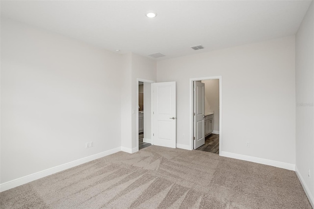 unfurnished bedroom featuring recessed lighting, visible vents, dark carpet, ensuite bath, and baseboards