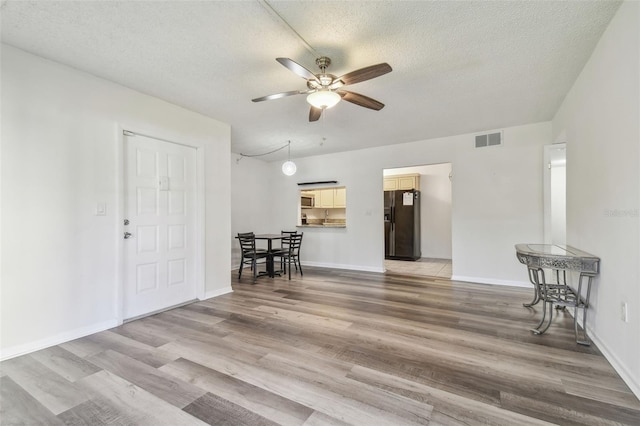 living room with ceiling fan, hardwood / wood-style floors, and a textured ceiling