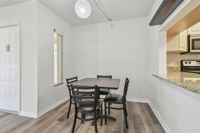 dining area with a healthy amount of sunlight, a textured ceiling, light hardwood / wood-style floors, and a chandelier