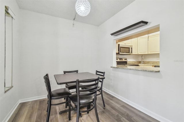 dining space featuring sink, an inviting chandelier, a textured ceiling, and dark hardwood / wood-style floors