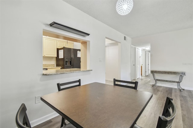 unfurnished dining area with a textured ceiling, light hardwood / wood-style flooring, and an inviting chandelier