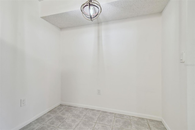 empty room with a textured ceiling and light tile patterned floors