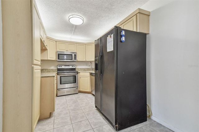 kitchen featuring stainless steel appliances, a textured ceiling, and light tile patterned floors