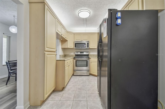 kitchen featuring a textured ceiling, light stone counters, light tile patterned floors, hanging light fixtures, and appliances with stainless steel finishes