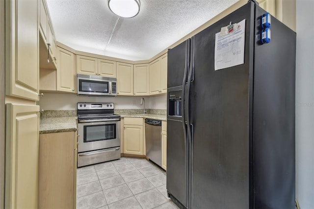 kitchen with light brown cabinetry, appliances with stainless steel finishes, light tile patterned floors, and sink