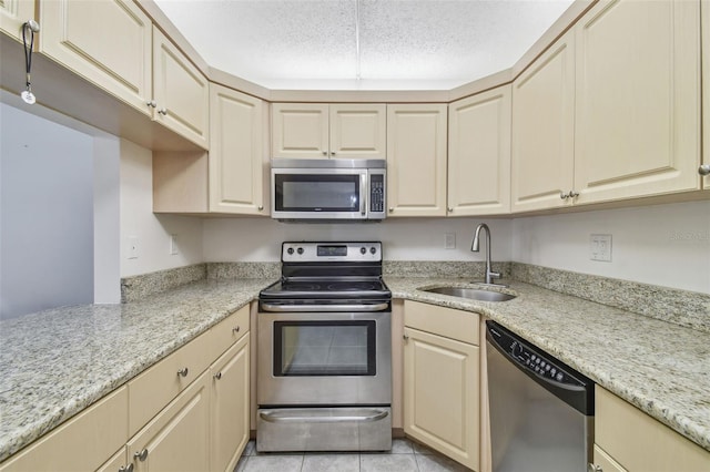 kitchen with stainless steel appliances, light stone countertops, light tile patterned floors, and sink